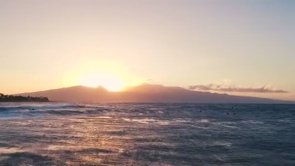 Repülés alatt a naplementét az óceán hullámai úszó szörfösök. Csodálatos naplemente légi kilátással az óceánra — Stock videók