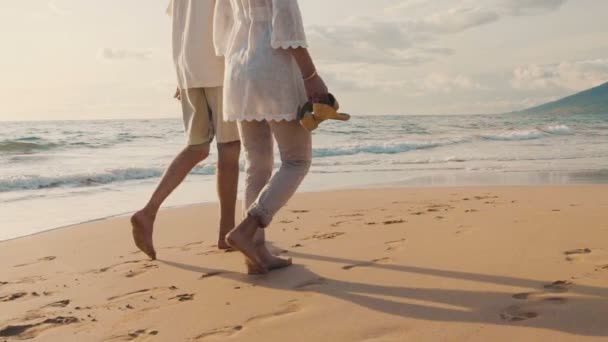 Sunset procházka na luxusní pláži. Starší dvojice drží ruce a procházky dolů po pláži při západu slunce jak se mojí nohy — Stock video