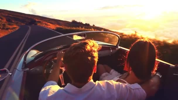 Счастливая пара едет по проселочной дороге на закат в классическом винтажном спорткаре Стоковое Видео