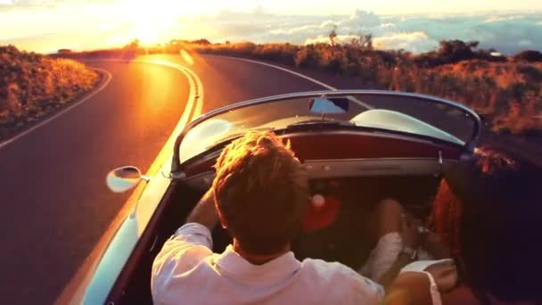 Счастливая пара едет по проселочной дороге на закат в классическом винтажном спорткаре — стоковое видео