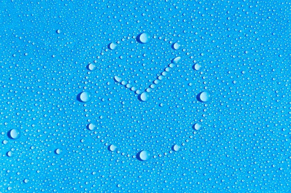 Drops of water in the form of a dial are located on a wet blue background. Dial made of water drops. Abstract blue background. Time is water.