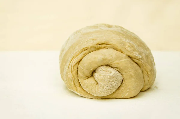Hamur mayası, mutfak masasının üzerine serpilmiş bir çörek şeklinde. Ekmeğin buklelerine özel bir odak ile serpiştirilmiş un serpiştirilmiş..