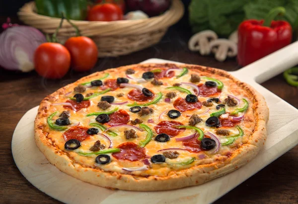 Tüm supreme pizza pişmiş taze pişmiş ve fırın sıcak ahşap yüzeyde hizmet