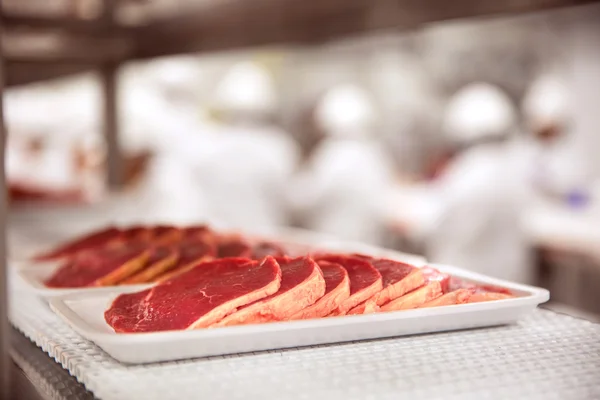 Potongan daging yang diportasikan pada styrofoam pada ban konveyer di pabrik pengolahan — Stok Foto