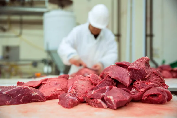 Trabalhador corta carne açougueiro manipulação de cortes de primeira escolha — Fotografia de Stock