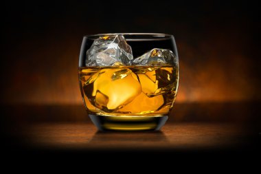 Single glass of whisky whiskey bourbon on ice on top of a wood bar table and wooden background clipart