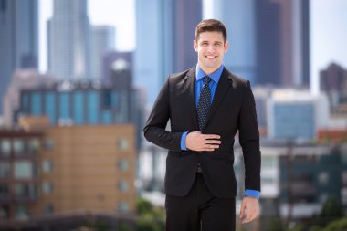 Happy confident attractive businessman in a suit downtown skyline rooftop