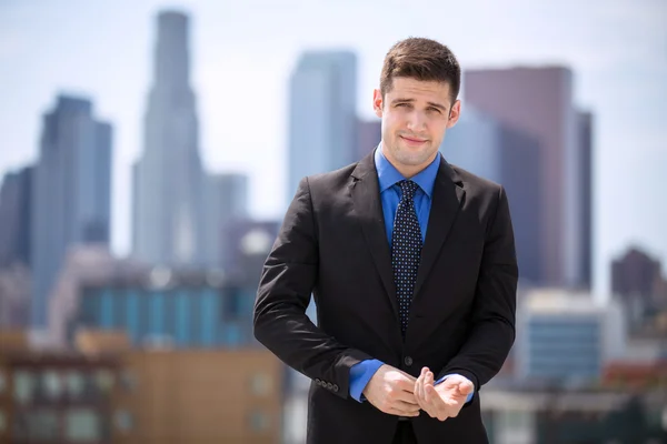 Charming handsome business man adjusting suit cuffs and smiling cunning confidence in city — Stock Photo, Image