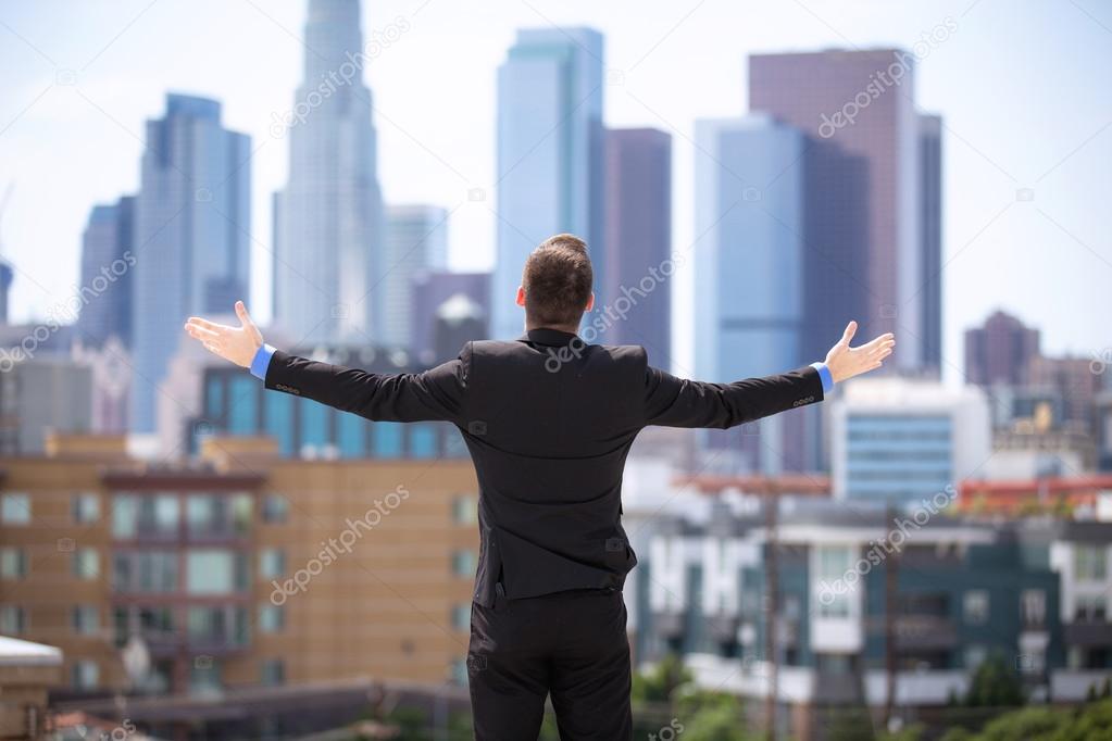 Glory happy businessman arms raised to the sky downtown skyline buildings