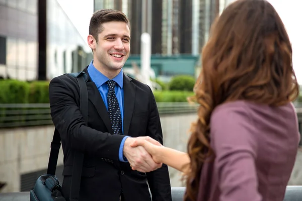 Handshake entre dois empresários atraentes sorrindo edifícios do centro da cidade — Fotografia de Stock