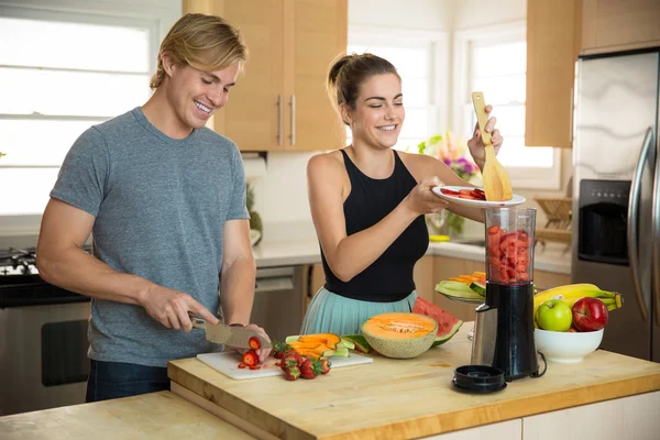 Beautiful woman home in kitchen making a smoothie with blender fresh fruit ingredients organic — Stok fotoğraf