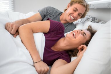 Lovers playing in bedroom bed playful laughing smiling in the morning foreplay friends