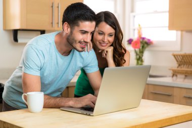 Man and woman video chat webcam with family on laptop computer social networking internet on kitchen counter