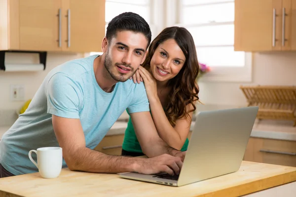 Husband and wife couple sharing a computer laptop social network laughing smiling searching for funny content with coffee — ストック写真