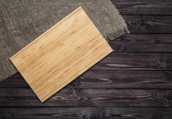 Cutting board on dark old wooden table. Top view