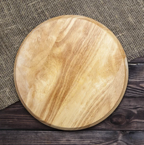 Placa de corte redonda em uma mesa de madeira, vista superior — Fotografia de Stock