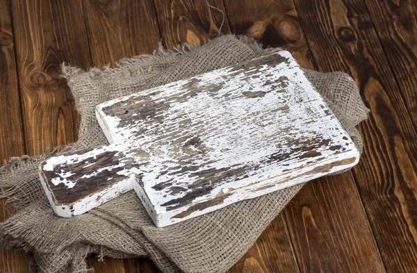 Placa de corte velha com pano de serapilheira na mesa de madeira — Fotografia de Stock