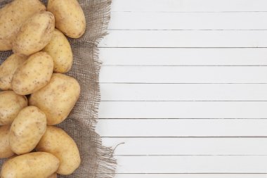 Beyaz ahşap zemin, üstten görünüm üzerine çuval bezi ile ham patates