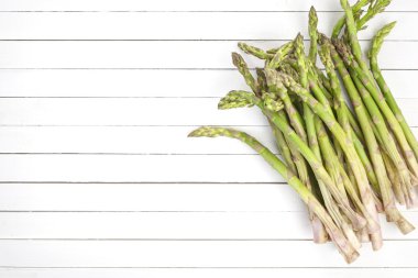 Beyaz ahşap zemin üzerinde taze yeşil kuşkonmaz. Üstten Görünüm