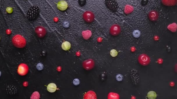 Fresh wild berries on black wooden background, top view — Stock Video