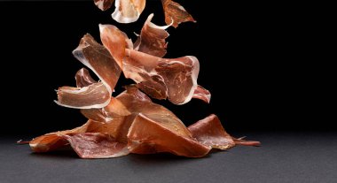 Düştü jambon dilimleri, siyah arka planda çiğ domuz jambonu.