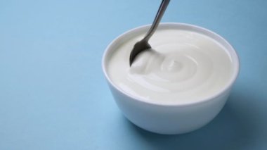 Mavi arka planda bir kase ekşi krema, Yunan yoğurdu.