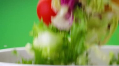 Yeşil arka planda kaseye düşen taze salata.