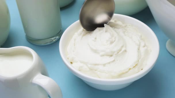 Χτυπημένη κρέμα γάλακτος με κουτάλι σε μπλε φόντο, κορυφαία προβολή — Αρχείο Βίντεο