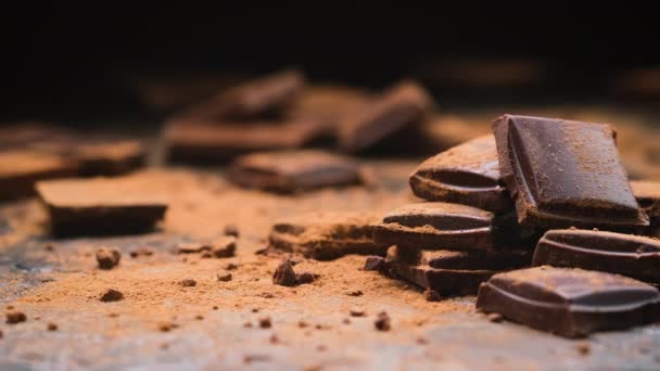 Barras de chocolate negro roto sobre fondo negro, pila de trozos de chocolate — Vídeo de stock