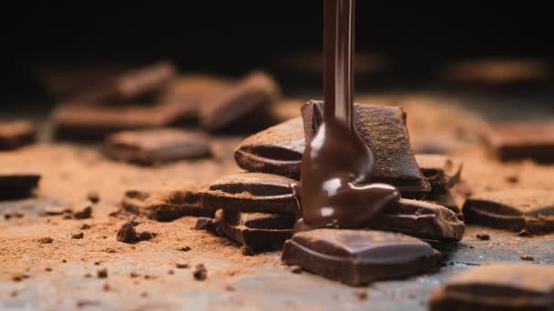 Chocolate vertiendo en barras de chocolate sobre fondo de pizarra negro — Vídeos de Stock