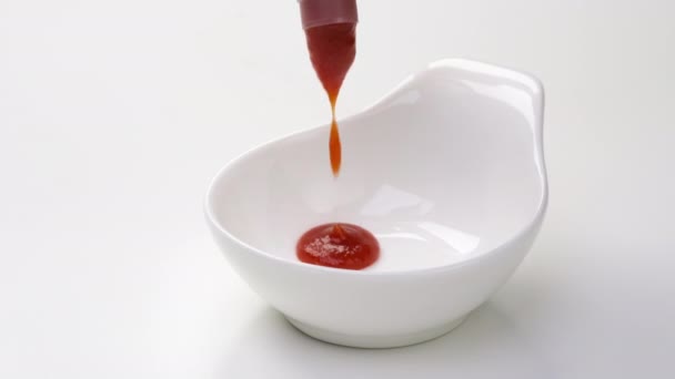Verter ketchup en un tazón sobre fondo blanco — Vídeo de stock