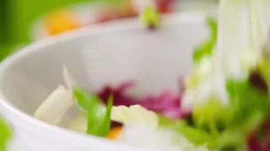 Yeşil arka planda kaseye düşen taze salata.