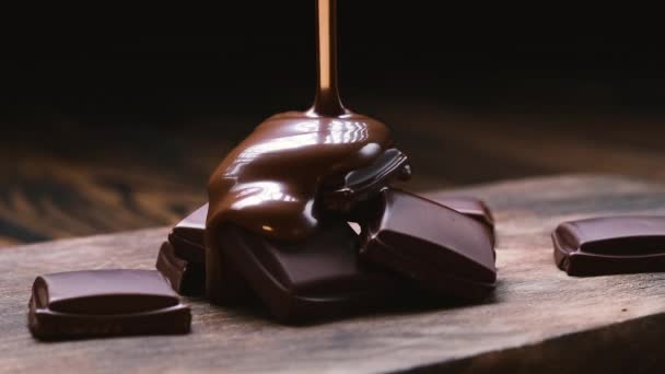 Chocolate vertiendo en barras de chocolate sobre fondo negro — Vídeos de Stock