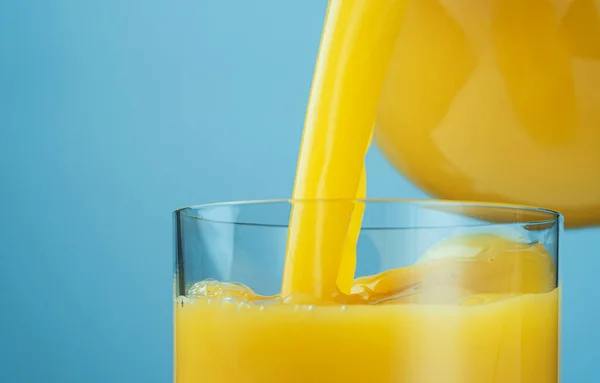 Sumo de laranja derramando de jarro em vidro — Fotografia de Stock