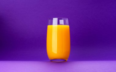 Bir bardak portakal suyu menekşe arkaplanda izole edilmiş ve fotokopi alanı var. Taze narenciye suyu, portakal kokteyli.