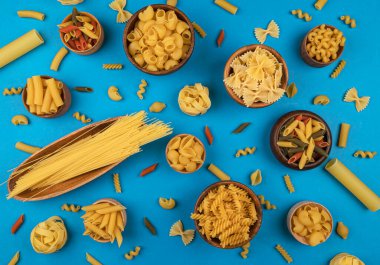 Mavi arkaplanda metin ve üst görünüm için kopyalama alanı olan farklı makarna türleri