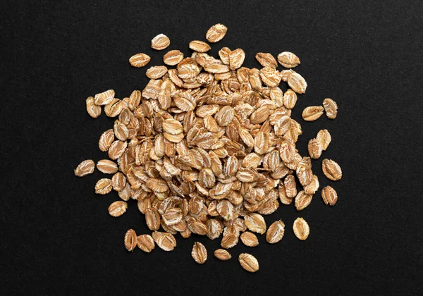 Top view of oat flakes on black background — Stock Photo, Image