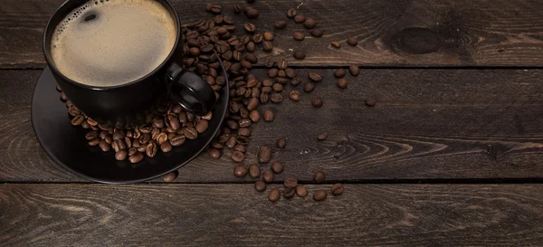 Чашка кави з зернами, дерев'яний фон — стокове фото