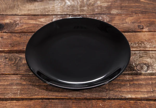 Чорна тарілка на дерев'яному фоні — стокове фото