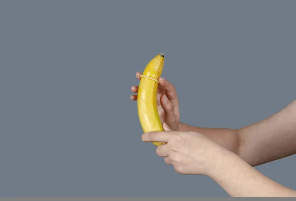 Female Hand Puts Condom Banana Safety Sex Concept Gray Background — Stock Photo, Image