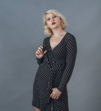 Genç bir kadın, beyaz saçlı, siyah elbiseli, gri arka planda, stüdyoda..