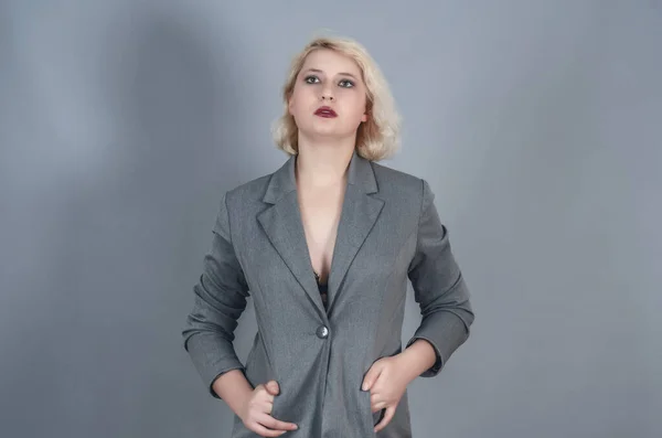 迷人的金发女孩穿着灰色夹克在工作室里的性感肖像 — 图库照片