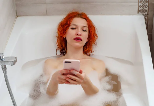 Młoda Kobieta Leżąca Łazience Telefonem Pisze Wiadomość Przez Telefon Rozmawia — Zdjęcie stockowe
