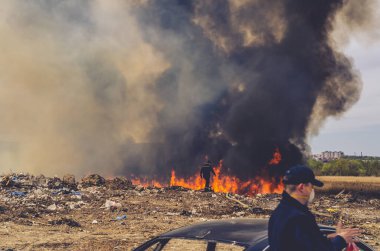 İtfaiyeci kuru otlardan çıkan büyük ateş ve dumana bakar.