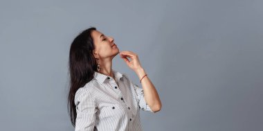 Orta yaşlı bir kadın elini çenesinin yakınında tutuyor..