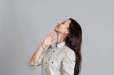 Orta yaşlı bir kadın elini çenesinin yakınında tutuyor..