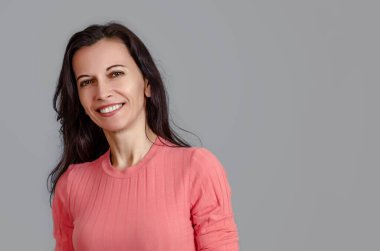 Gri arka planda sevimli, gülen kadın portresi