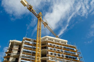 Modern inşaat, cam pencere panelleri, iskele vinci olan evin ön cephesini tamamlıyor.