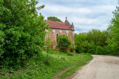 Ağaçların arkasında kırmızı tuğlalar olan terk edilmiş eski bir kilise.