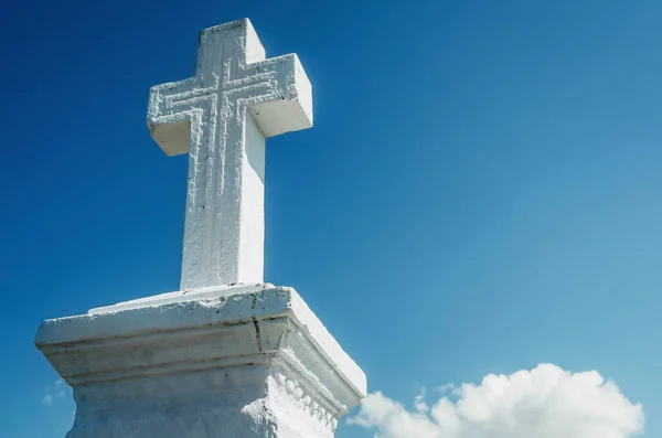 Ancient white stone cross on background of blue sky.